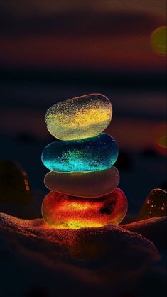 593b7b854b4473aaa39114fd6fc5708e Phần này có thể chứa: three rocks stacked on top of each other in the sand at night with colorful lights