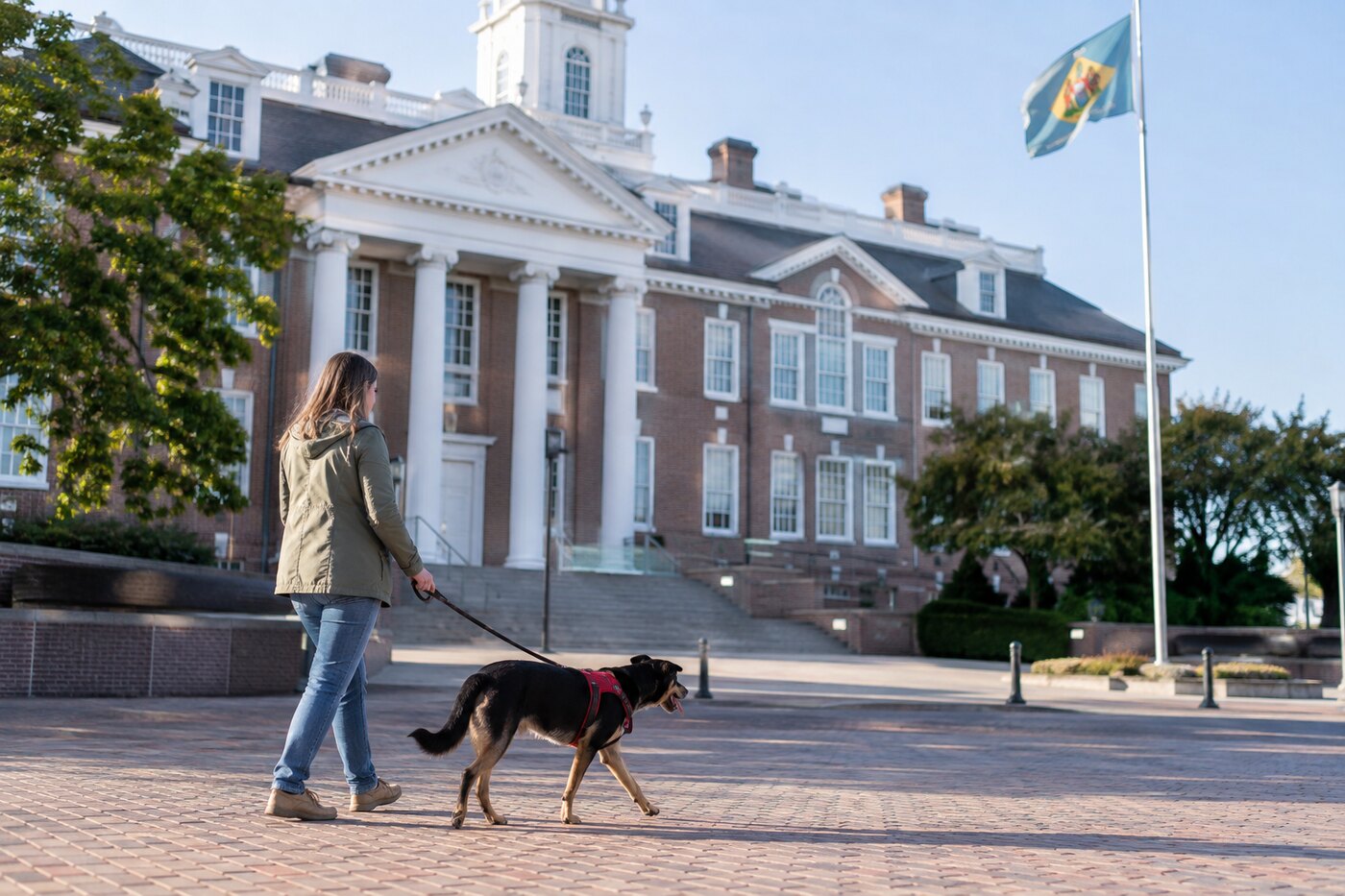 A person walking a leashed dog outside a state legislative building