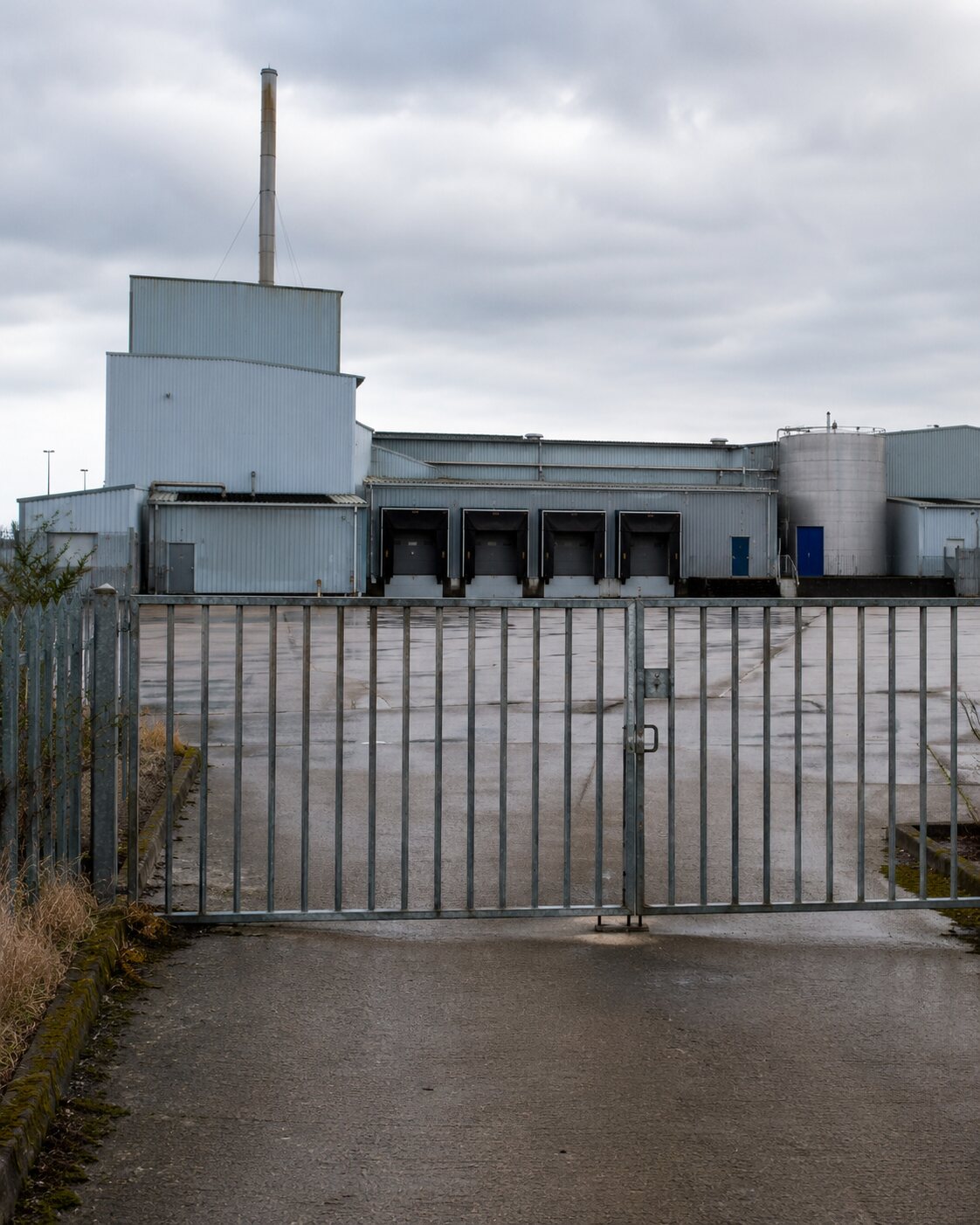 An empty industrial livestock-processing facility stands behind a locked gate.